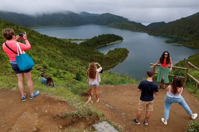 Tourists take pictures at a scenic viewpoint overlooking Lagoa do Fogo (Lake of Fire), a crater lake within the Agua de Pau Massif stratovolcano in the centre of Sao Miguel Island in the Azores archipelago, Portugal July 3, 2024. REUTERS/Darrin Zammit Lupi/File Photo