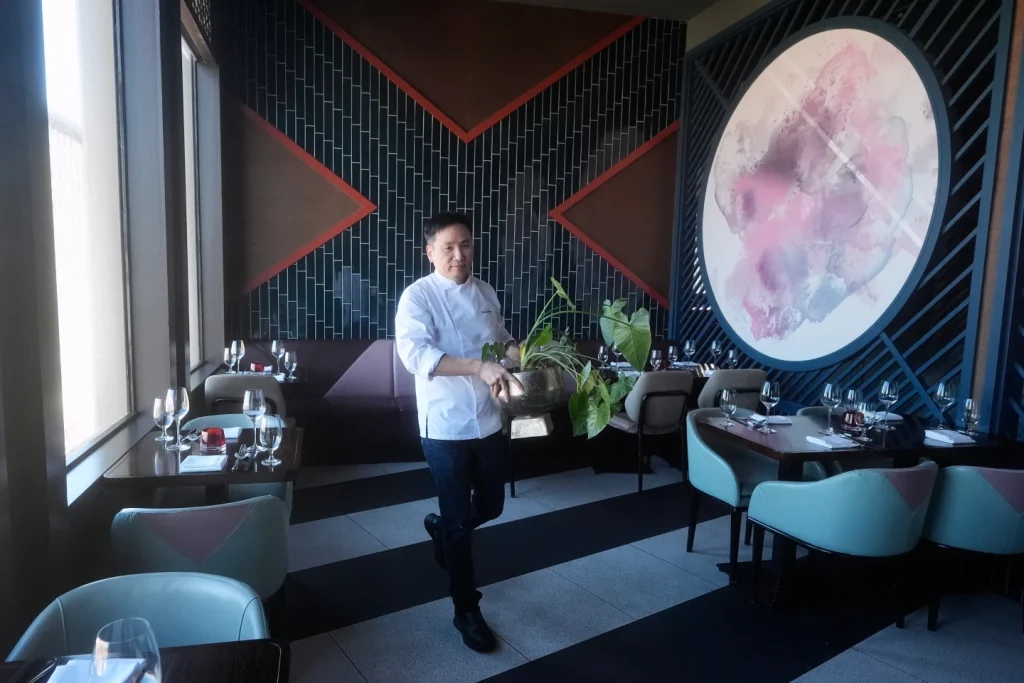 Malaysia-born chef and restaurant owner Ho Chee Boon moves a plant from a dining area while giving an interview at his Empress by Boon restaurant in San Francisco, Thursday, Jan. 8, 2026. (AP Photo/Jeff Chiu)