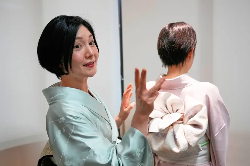 Nao Shimizu, Representative Director of Kimono Sunao Co., Ltd., left, demonstrates various ways of tying an obi on dressing assistant Emiko Terai during a kimono presentation in Tokyo on Tuesday, Nov. 11, 2025. (AP Photo/Eugene Hoshiko)