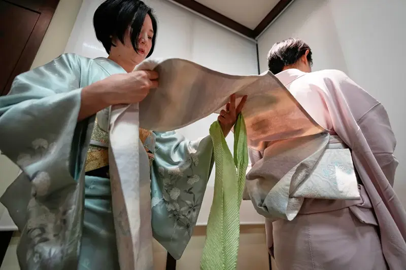 Nao Shimizu, Representative Director of Kimono Sunao Co., Ltd., left, demonstrates various ways of tying an obi on Emiko Terai during a kimono presentation in Tokyo on Tuesday, Nov. 11, 2025. (AP Photo/Eugene Hoshiko)