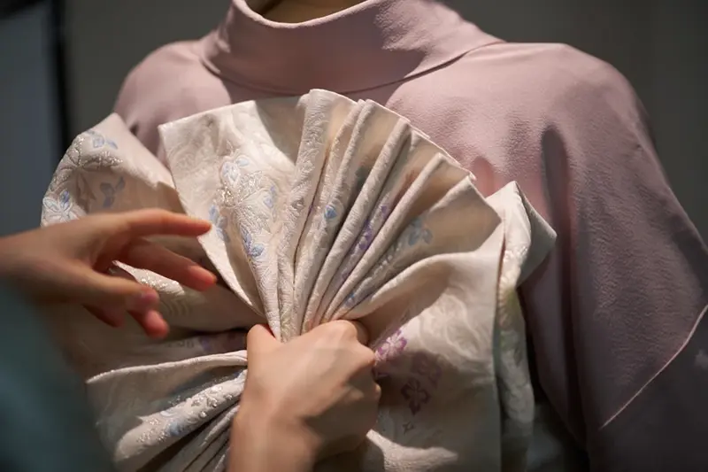 Nao Shimizu, Representative Director of Kimono Sunao Co., Ltd., left, demonstrates various ways of tying an obi on assistant Emiko Terai during a kimono presentation in Tokyo Tuesday, Nov. 11, 2025. (AP Photo/Eugene Hoshiko)