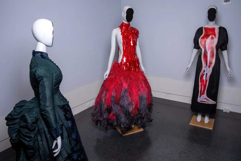 A vintage walking dress, from left, an Alexander McQueen dress, and a Christopher Kane dress are held in preparation for The Metropolitan Museum of Art’s spring exhibition, “Costume Art,” on Thursday, Feb. 12, 2026, in New York. (Photo by Charles Sykes/Invision/AP)