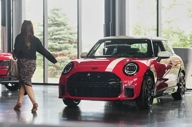 A shopper passes by an unsold 2026 Cooper S John Cooper Works 1965 Victory Edition hardtop on display in the showroom of a Mini dealership Friday, June 26, 2026, in Highlands Ranch, Colo. (AP Photo/David Zalubowski, File)