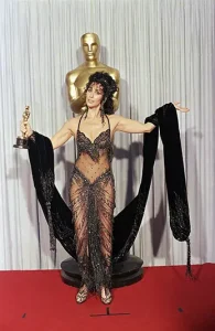 Cher, wearing a Bob Mackie black-sequined gown, poses with her Oscar after winning the award for best actress for her role in "Moonstruck" at the 60th Annual Academy Awards in Los Angeles on April 12, 1988. (AP Photo/Lennox McLendon, File)
